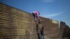 Migranti prelaze ogradu na granici sa Meksikom