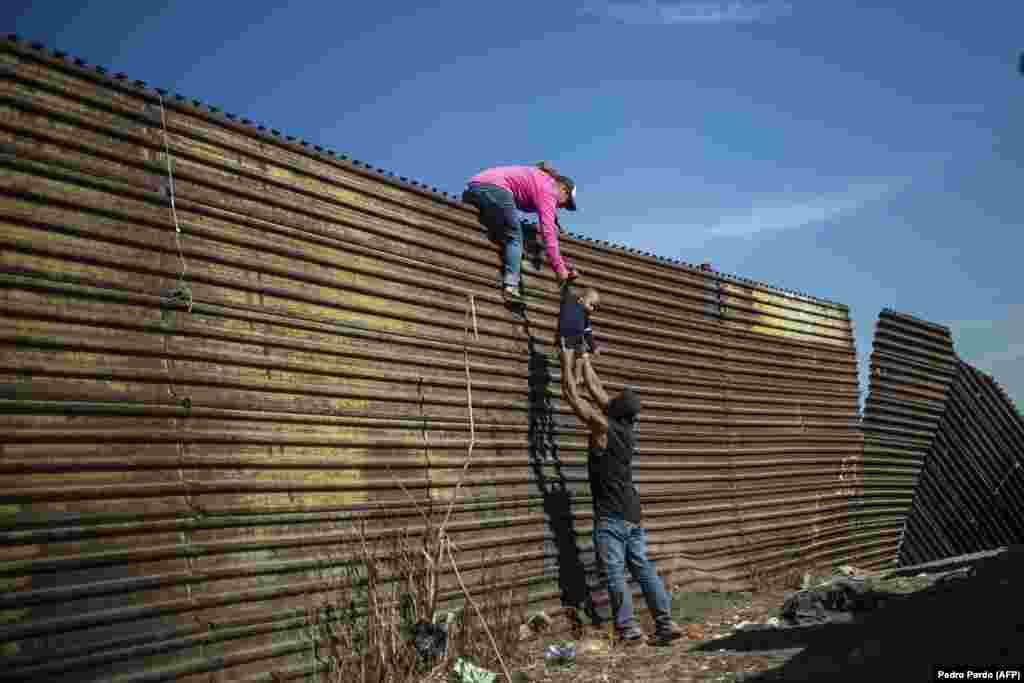 A group of migrants climb a border fence between Mexico and the United States, near El Chaparral border crossing, in Tijuana, Mexico, on November 25, 2018. Spot News: Third Prize, Singles - Pedro Pardo, Agence France-Presse