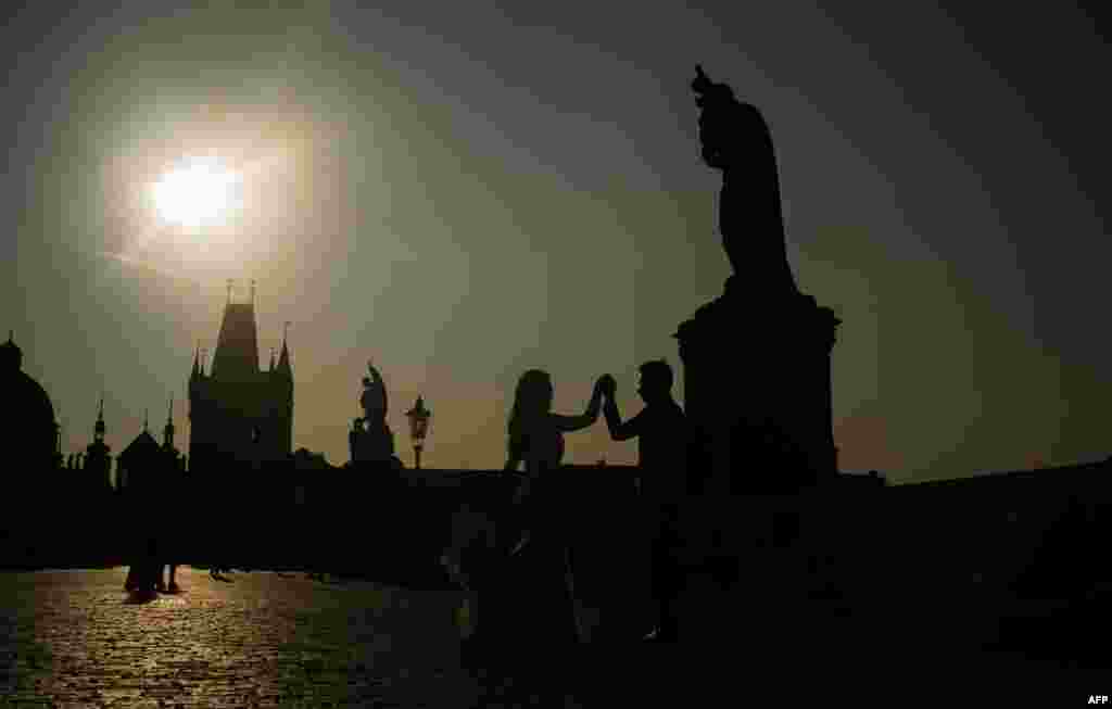 A bride and groom pose for a photographer on the Charles Bridge in the early morning in Prague, Czech Republic. (AFP/Michal Cizek)