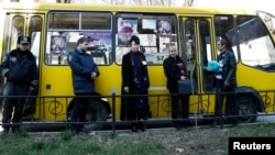 Election commission officials accompanied by the police wait for a bus to deliver ballots for the upcoming referendum in the Crimean capital Simferopol. 