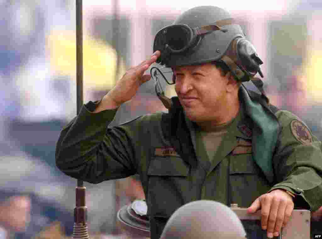 Chavez salutes from atop an armored vehicle during Army Day in Caracas on June 24, 2005.