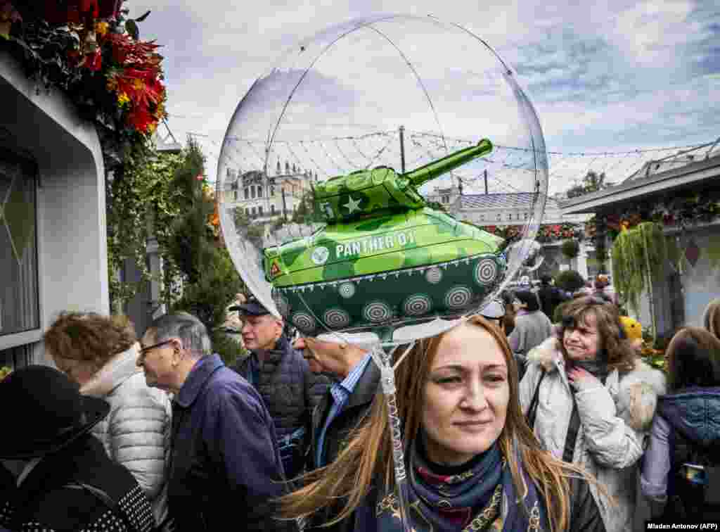 A woman carries a children&#39;s balloon with a tank inside during an autumn festival held in central Moscow. (AFP/Mladen Antonov)