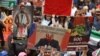 Демонстранты держат фотографии президента России Владимира Путина и президента Сирии Башара аль-Асада в знак протеста против участия России в сирийской гражданской войне и в поддержку беженцев и лиц, ищущих убежища в Сиднее, 11 октября 2015 года, Австралия