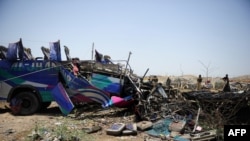 FILE: Policemen stand beside the wreckage of a bus after a Pakistan air force fighter plane crashed at a bus terminal on the outskirts of Karachi in June 2014.