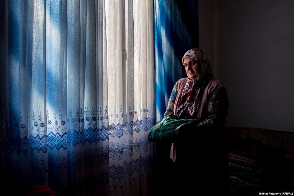 Rabija Avdić drži u rukama džemper od brata koji je ubijen tokom genocida u Srebrenici.