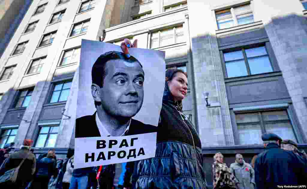 A protester holds a picture of Russian Prime Minister Dmitry Medvedev bearing an inscription reading &quot;An Enemy Of The People&quot; during a rally against pension reform in front of the State Duma, the lower house of parliament, in Moscow. The Russian parliament on September 26 unanimously approved President Vladimir Putin&#39;s amendments to a hugely unpopular pension reform that has led to a rare outburst of public anger in the country (AFP/Yuri Kadobnov)