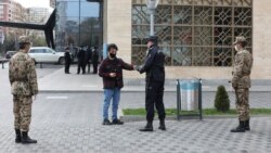 Баку көшесіндегі азаматтың биліктен алған СМС-рұқсаты бар-жоғын тексеріп тұрған күш құрылымдары өкілдері. 6 сәуір 2020 жыл.