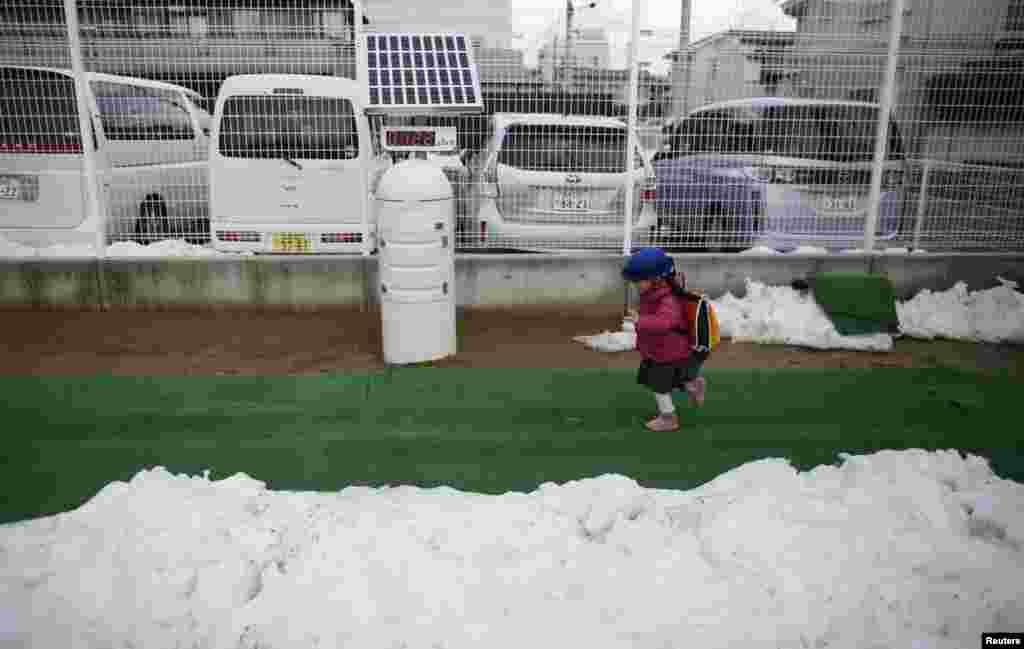 A girl runs past a Geiger counter as she arrives at school.