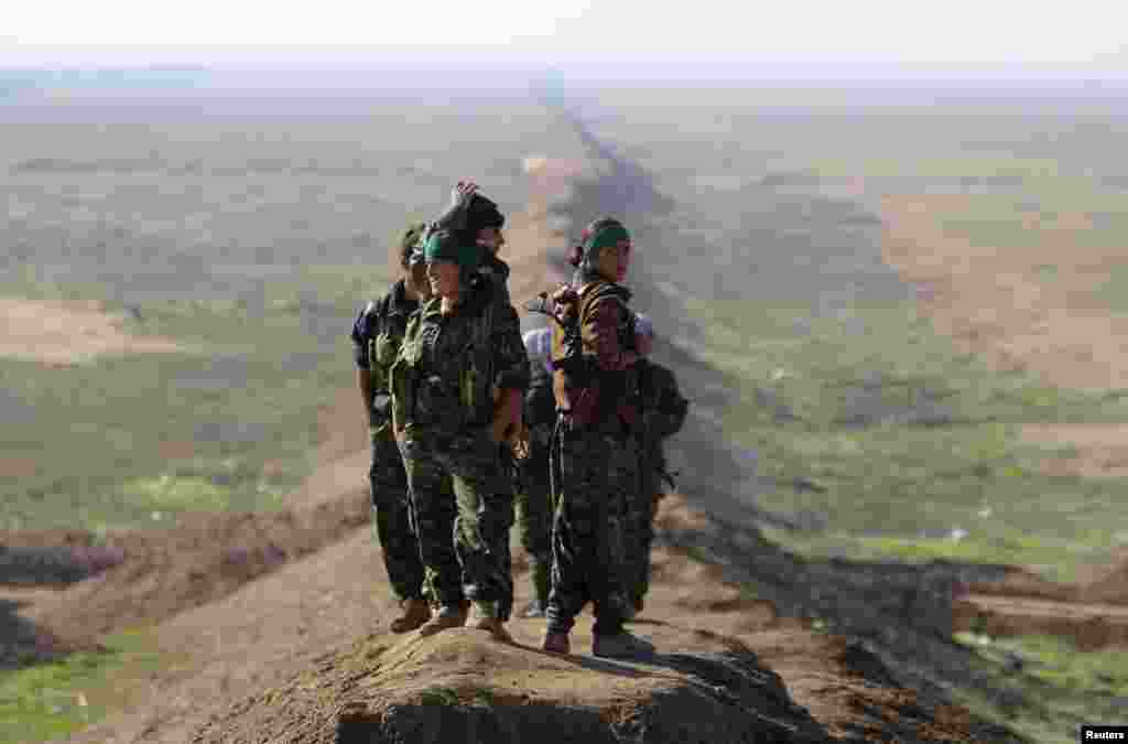 Female fighters with the Kurdish People's Protection Units (YPG) stand near the border between Syria and Iraq, close to the Iraqi town of Snoun. (Reuters)