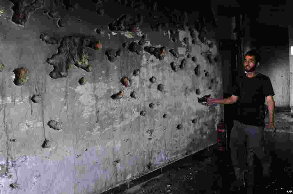 An Afghan policeman points to shrapnel at the site of a suicide attack in in Jalalabad, the capital of Nangarhar Province, which killed at least seven people on May 12. (AFP/Noorullah Shirzada)