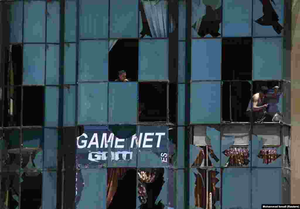 A shopkeeper removes broken glass from a shattered window at his shop near the site of an explosion in Kabul. (Reuters/Mohammad Ismail)