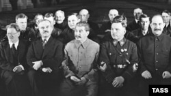 У першому ряду сидять (з права на ліво) Мікоян, Ворошилов, Сталін, Молотов, Калінін