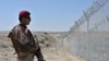 A Pakistani Army soldier stands guard along a border fence at the Afghan border near the Punjpai area of Quetta in Balochistan Province.