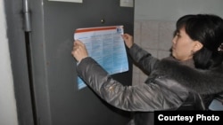 A social worker with the NGO Sana Sezim hangs up a flyer on how to avoid becoming a victim of human trafficking and labor exploitation at a police station in Shymkent, Kazakhstan.