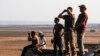 A picture taken on July 23, 2018 from the Israeli-annexed Golan Heights shows Israelis looking out across the border watching as warplanes backing a Syrian-government offensive carry out air strikes in the southwestern Syrian province of Daraa.