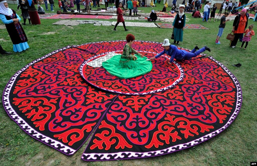 A woman wearing a traditional Kyrgyz dress sits on felt carpets at the seventh International Festival of Kyrgyz National Applied Arts in the village of At-Bashi, 400 kilometers from Bishkek, on June 28. (AFP/Vyacheslav Oseledko)