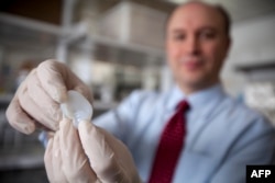 Larry Bonassar of Cornell University holds a fabricated ear printed with a 3D printer in his lab.