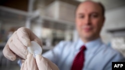 Larry Bonassar, profesor, drži u ruci uho napravljeno 3D tehnikom