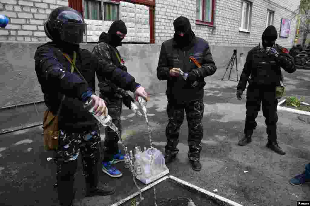 Ýüzi perdeli adamlar, ýangyç bombasynda ulanmak üçin, arak çüýşelerini boşadýarlar.