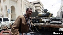 Libya -- A rebel fighter walks beside a captured pro-government's forces tank in Tripoli street, Misurata, 22Apr2011