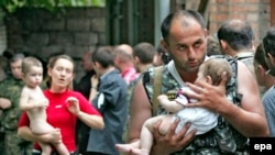 A soldier carries a baby after the hostage-takers released 26 women with their children from the Beslan siege on September 2, 2004.