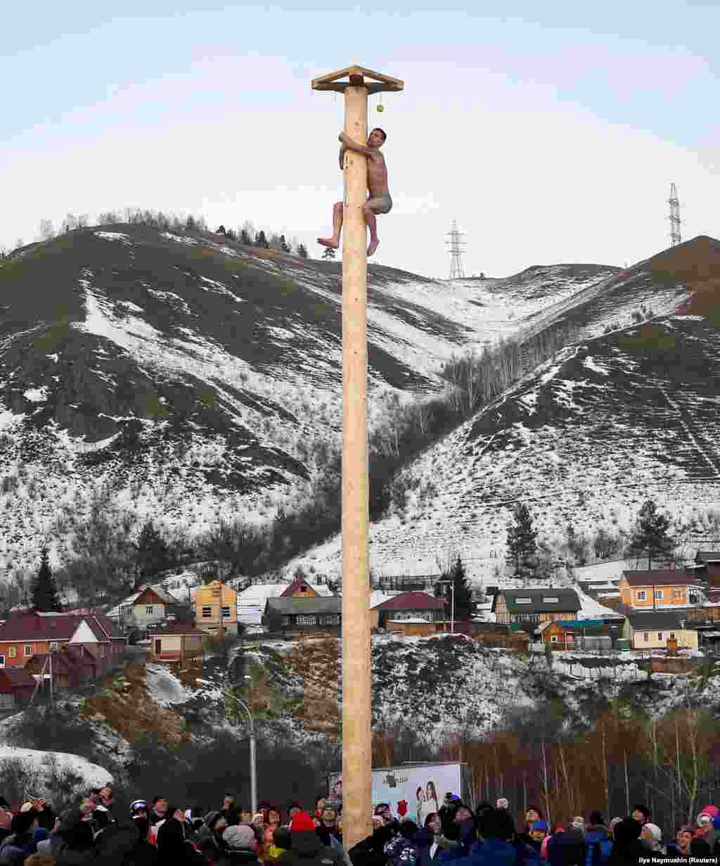 Еще одна традиция &ndash; восхождение на масленичный столб, на вершине которого размещают разнообразные призы и подарки. Человек без посторонней помощи или каких-либо технических устройств должен забраться на холодный ледяной столб. На фото: раздетый мужчина лезет на масленичный столб в Красноярске, 26 февраля.