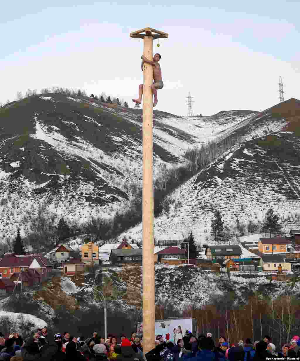 A Krasnoyarsk man moments away from claiming his prize after scaling a stripped tree-trunk as part of Maslenitsa celebrations on February 26. &nbsp;