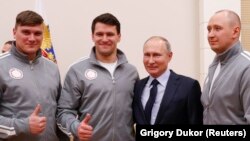 President Vladimir Putin (second left) poses for a selfie during a meeting on January 31 with Russian athletes and team members who will take part in the upcoming Winter Olympic Games as neutral athletes.