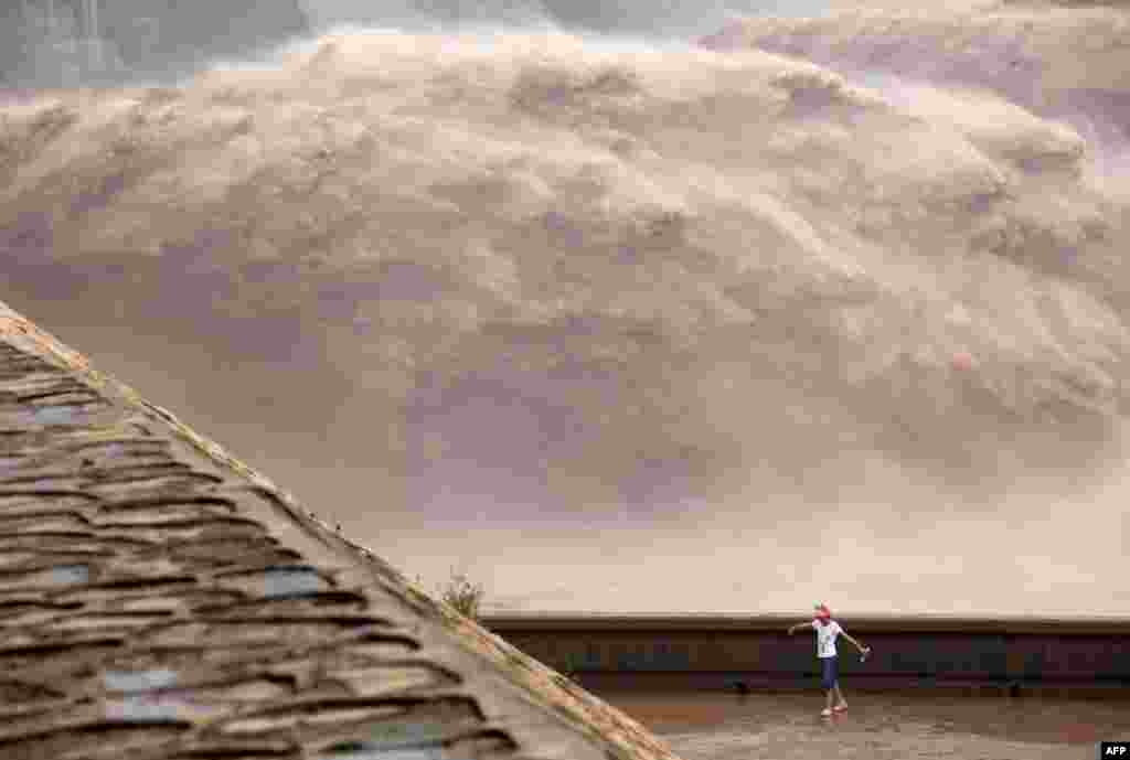 A girl plays on the edge of the Xiaolangdi Reservoir as it withstands the release of Yellow River floodwaters for the second time since the end of June in central China&#39;s Henan Province. At least 295 people have been confirmed dead or missing after rainstorms and Typhoon Soulik hit China. (AFP)