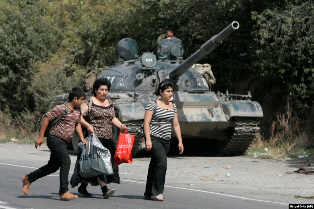 Грузинські біженці проходять повз російську броньовану машину в селі Іґоеті, за 50 кілометрів від Тбілісі, 16 серпня 2008 року