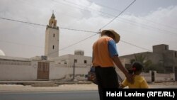 Мужчина с дочерью идет по улице в городе Бен Гардан.