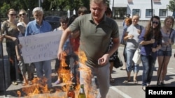 Активисты украинской организации "Наступ" сжигают изготовленные в России продукты в знак протеста против торговой войны Москвы. 16 августа 2013 года.