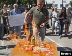 Активист украинской гражданской огранизации "Наступ" сжигает российские товары на акции протеста против Таможенного союза. Киев, 16 августа 2013 года.
