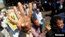 Supporters of Egypt's Muslim Brotherhood shout slogans against the military and the Interior Ministry as they gesture "Rabia" or "Four" during a protest in front of Al-Tawhid Mosque, which leads to Ramses Square in Cairo on August 23, 2013.