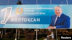 A woman pushes a pram in front of a poster with a portrait of former Kazakh President Nursultan Nazarbayev as the country prepares to the Day of the First President, celebrated on December 1, in Almaty in 2015.