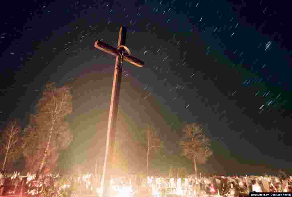 Candles illuminate graves in the village of Baruny in western Belarus. Photo by Alyaksandr Vasyukovich