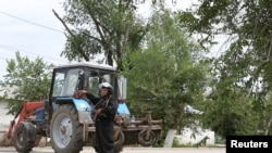 A Kazakh police officer blocks a street near the site of a firefight between Kazakh security forces and suspects linked to deadly attacks earlier this week on a National Guard base and several gun shops in Aqtobe.