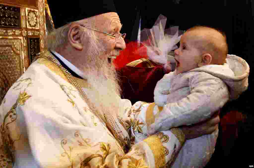 Ecumenical Patriarch Bartholomew I, spiritual leader of the Greek Orthodox world, plays with a baby after an Easter ceremony at St. George Church in Istanbul. (epa/Ulas Yunus Tosun)