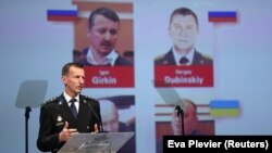 Wilbert Paulissen, one of the international investigators, speaks to reporters about the murder charges in front of photos of the suspects in Nieuwegein, the Netherlands, on June 19.