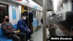 People wear protective face masks, following the outbreak of coronavirus, as they sit in a metro in Tehran, March 17, 2020