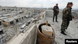 Forces loyal to Syrian President Bashar al-Assad stand atop of a building in a district of Aleppo that is now under government control. 