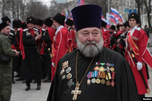 Православный священник на митинге, посвященном второй годовщине аннексии Крыма Россией. На заднем плане представители казачьей организации. Севастополь, 18 марта 2016 года