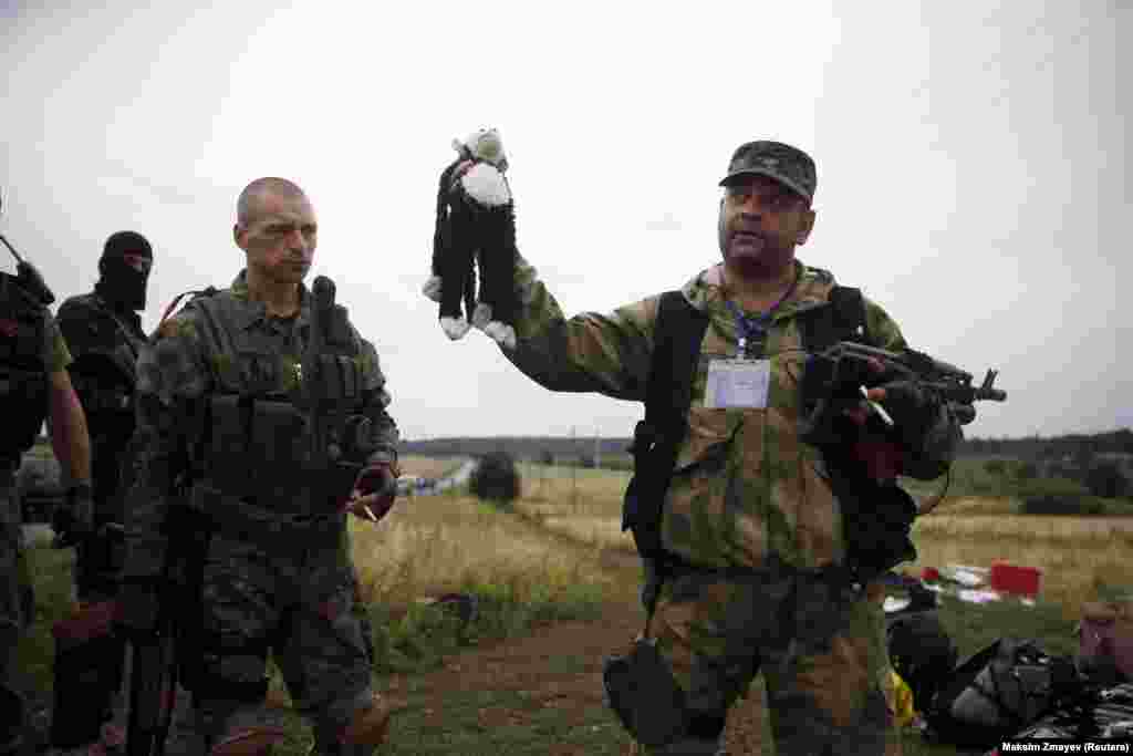 A pro-Russian separatist holds a child&#39;s stuffed toy found at one of the crash sites.