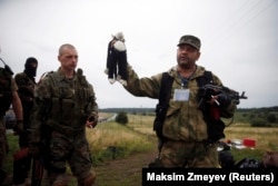 Un separatist pro-rus, ținând în mână o jucărie găzită pe locul prăbușirii avionului de pasageri MH17, în apropiere de Hrabove, 18 iulie 2014