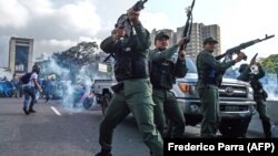 Members of the Bolivarian National Guard who joined the opposition fire into the air to repel forces loyal to President Nicolas Maduro who arrived to disperse a demonstration near La Carlota military base in Caracas on April 30.