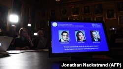 Fotografiile laureaților premiului Nobel pentru economie 2019 pe ecranul unui computer: americanul de origine indiană Abhijit Banerjee, americana de origine franceză Esther Duflo și americanul Michael Kremer.