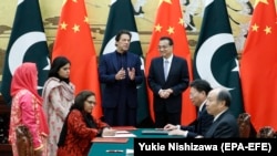 Pakistani Prime Minister Imran Khan (L) chats with Chinese Premier Li Keqiang (R) during a signing ceremony at the Great Hall of the People in Beijing, on October 8.