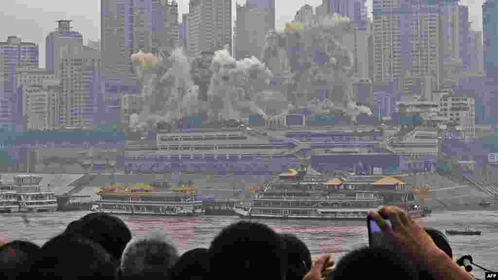 Residents watch as the Three Gorges Hotel and 32-story passenger terminal of Chongqing port are toppled in a controlled explosion to make way for new skyscrapers in southwest Chongqing municipality. (AFP PHOTO)