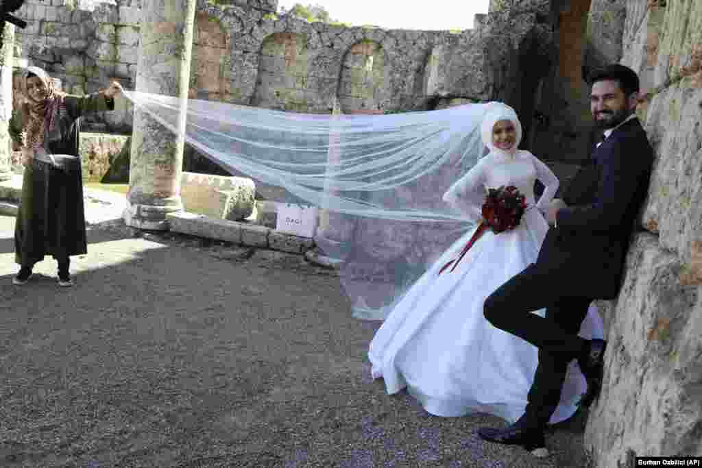 A newlywed Turkish couple pose for photos among the ruins of the ancient city of Perge, Antalya. (AP/Burhan Ozbilici)