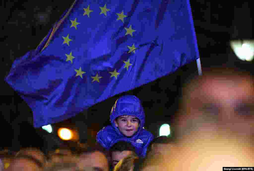 A young boy smiles under the EU flag in the Macedonian city of Prilep during a rally supporting the upcoming referendum to endorse a deal to give the country a new name -- North Macedonia -- which would end a long-running dispute between Macedonia and Greece and accelerate its bid to join NATO and the European Union. The referendum is scheduled for September 30. (EPA-EFE/Georgi Licovski)